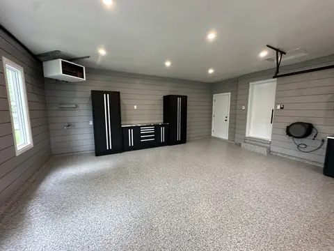 Garage with black cabinets, a stainless steel worktop and a flake epoxy floor